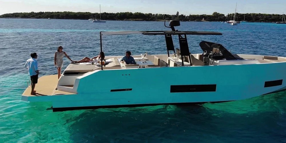 Modern yacht with people relaxing on clear turquoise water.