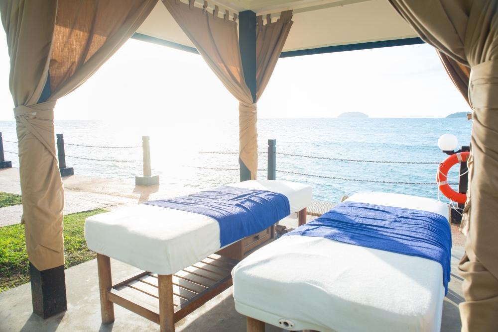 Oceanfront spa canopy with massage tables and island view.