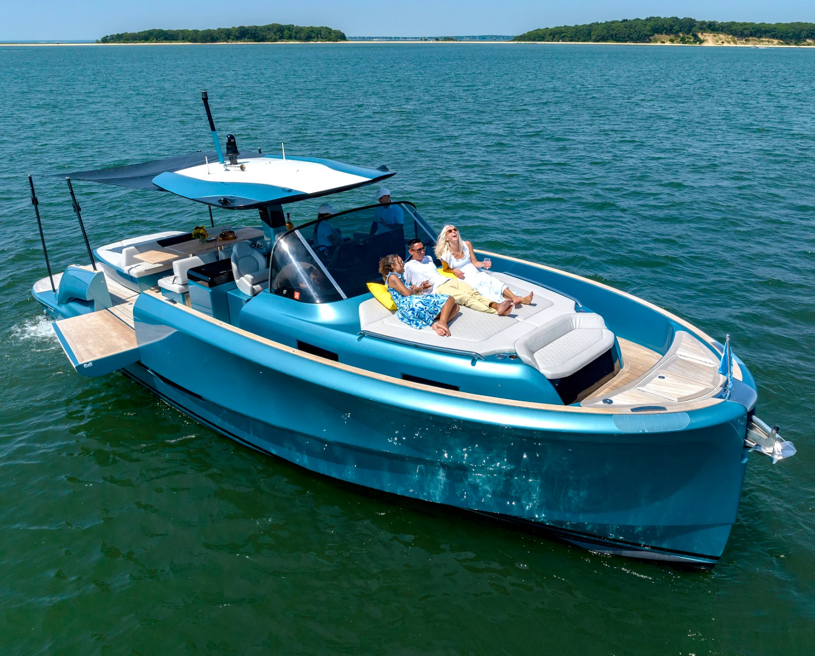 Modern yacht with sunbathers cruising on calm water.