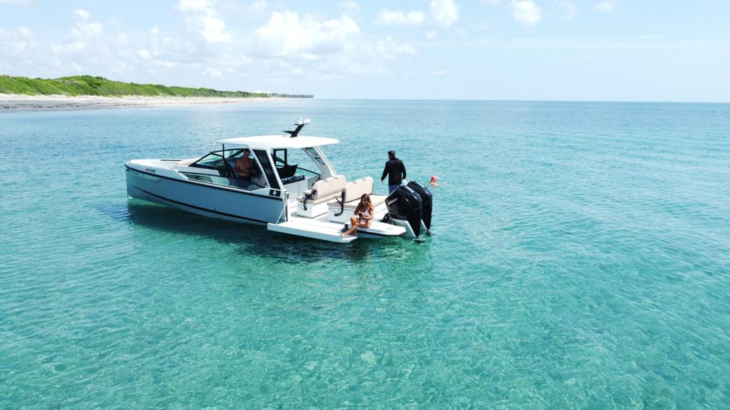 Modern motorboat floating on turquoise water near sandy coastline.