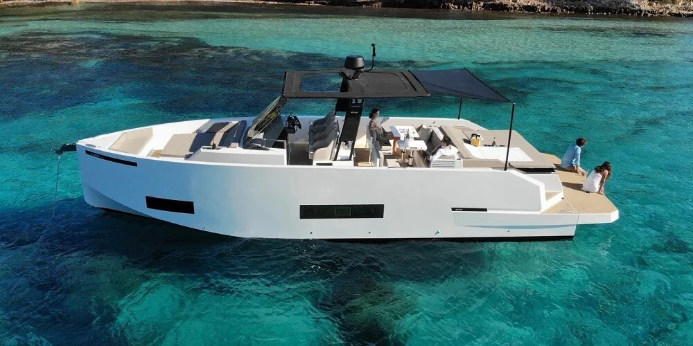 Modern yacht with passengers cruising on turquoise coastal waters.