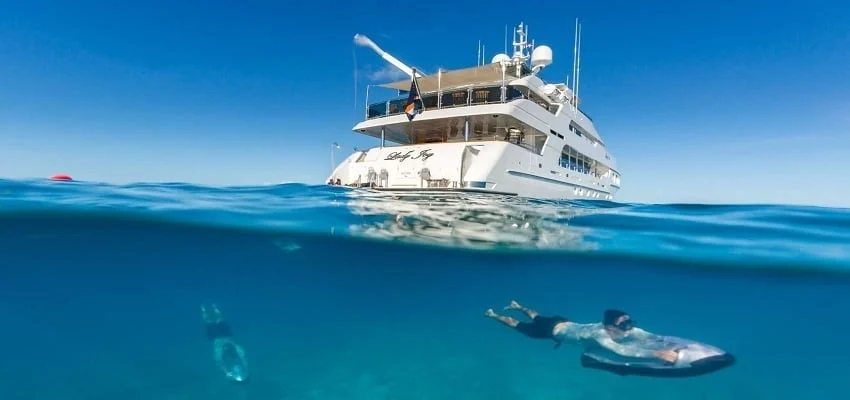 Man on a seabob near yacht on clear ocean surface.