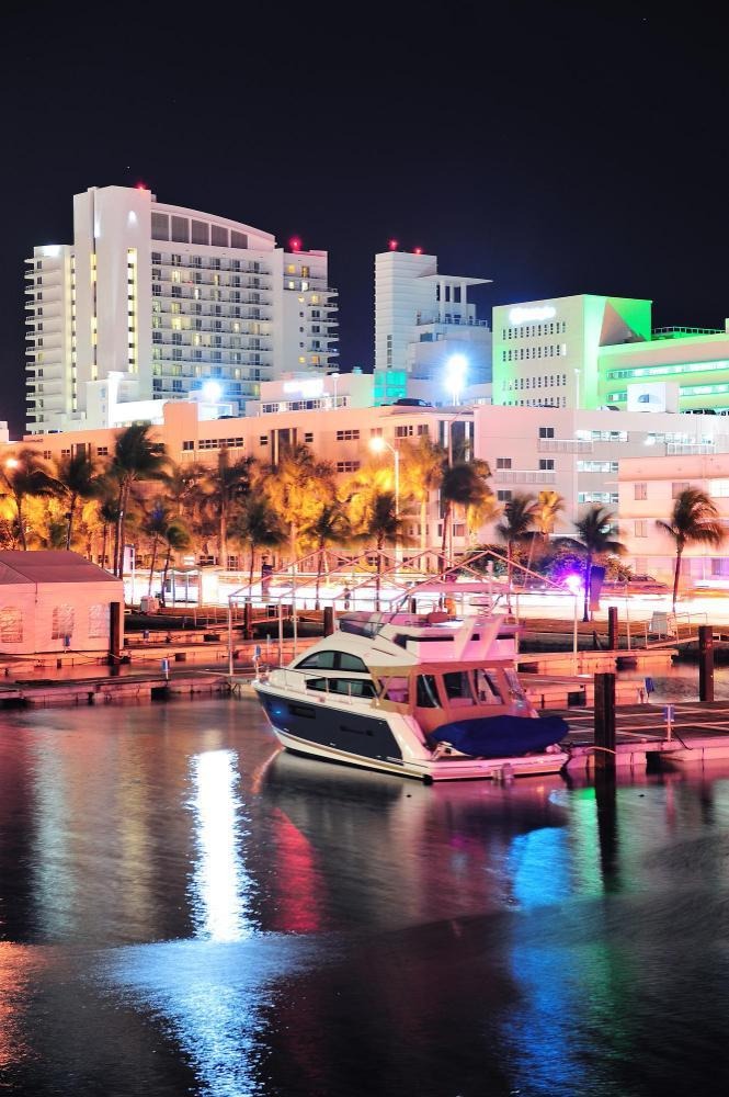 Docked yacht with city lights reflecting across nighttime marina.
