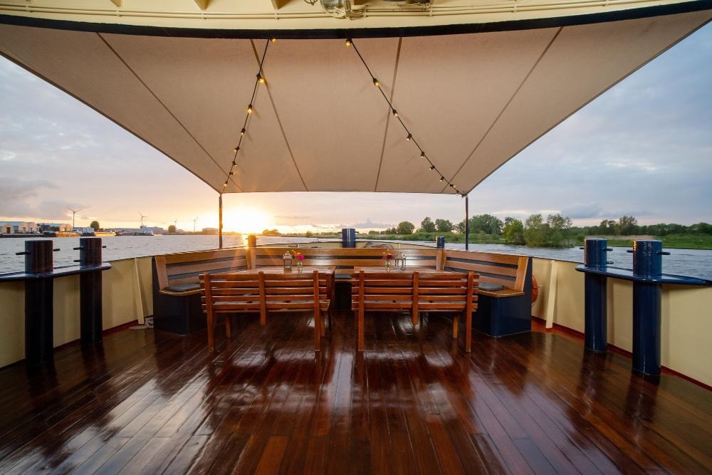 Sunset yacht deck with canopy, benches, Dining and waterfront view.