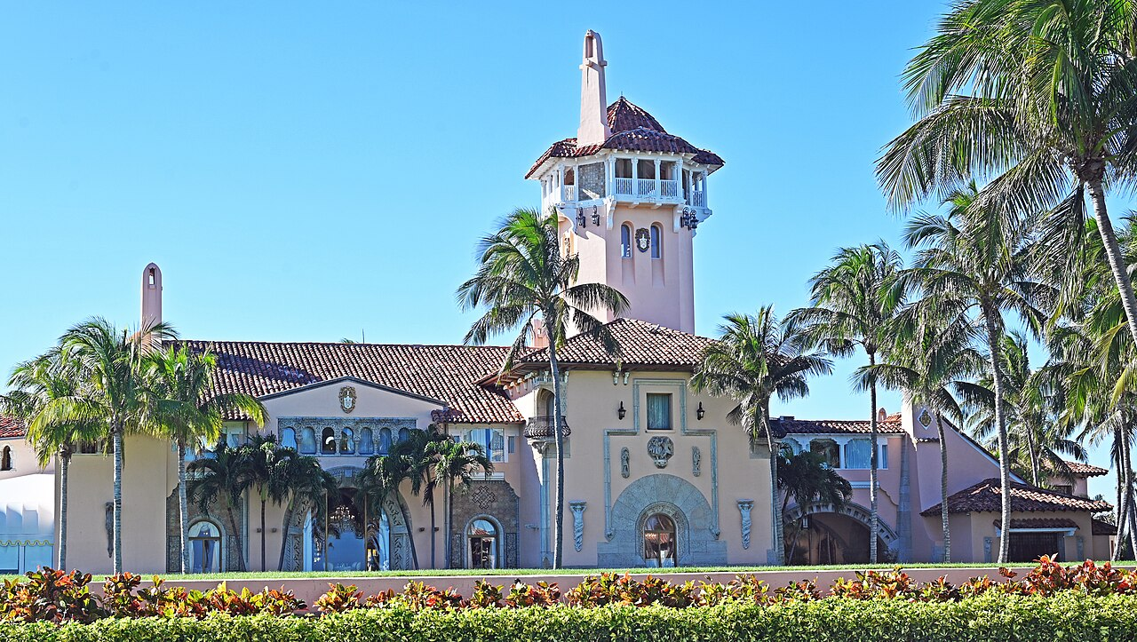 Mar‑a‑Lago mansion with tower, palm trees, and sunlight.