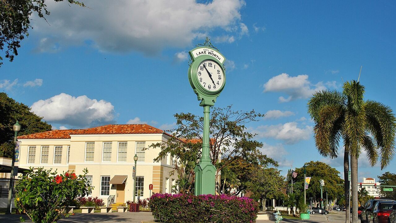  Lake Worth decorative clock surrounded by flowers and palm trees. 